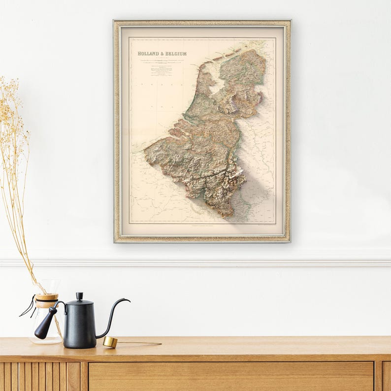 Pode incluir: Um mapa vintage da Holanda e da B&eacute;lgica em uma moldura de cor creme. O mapa &eacute; um mapa de relevo com cores marrom, verde e azul. O mapa &eacute; intitulado "Holland & Belgium" no canto superior esquerdo.