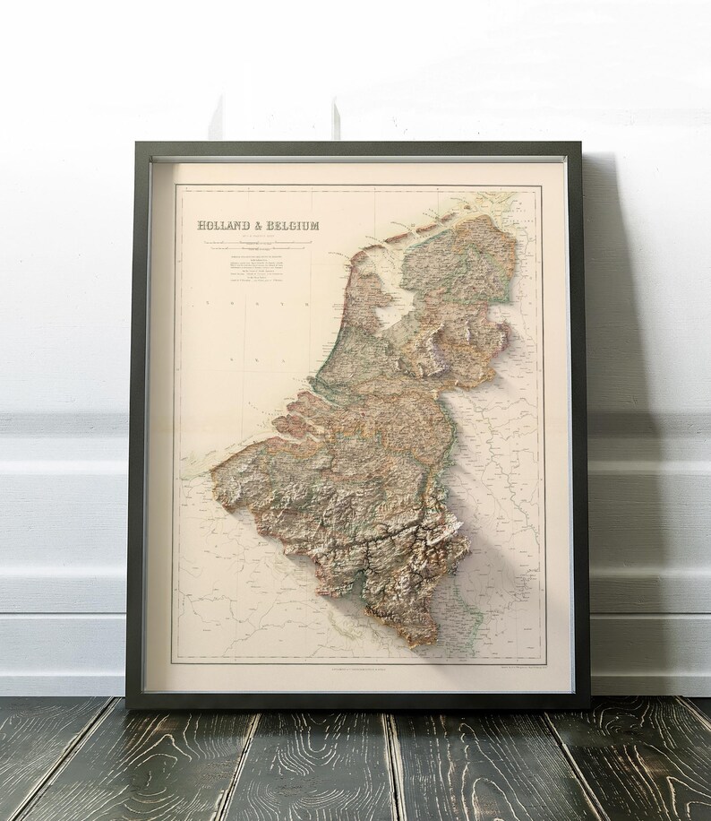 Pode incluir: Um mapa vintage da Holanda e da B&eacute;lgica, impresso em tons de marrom, verde e azul, com um efeito de relevo em relevo. O mapa est&aacute; emoldurado em uma moldura preta.