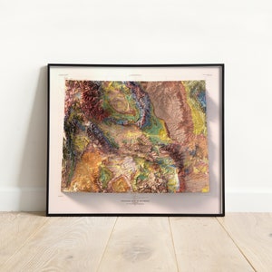 Puede incluir: Un mapa topogr&aacute;fico enmarcado de Wyoming con un dise&ntilde;o colorido, texturizado y 3D. El mapa est&aacute; impreso sobre un fondo crema con el t&iacute;tulo "Topographic Map of Wyoming" en la parte inferior.