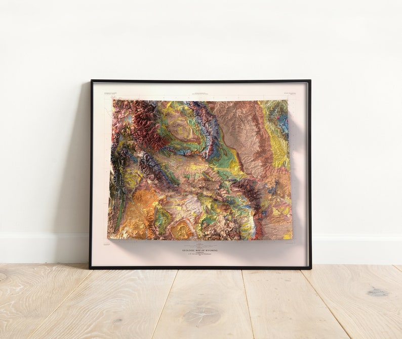 Puede incluir: Un mapa topogr&aacute;fico enmarcado de Wyoming con un dise&ntilde;o colorido, texturizado y 3D. El mapa est&aacute; impreso sobre un fondo crema con el t&iacute;tulo "Topographic Map of Wyoming" en la parte inferior.