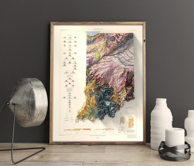 Op de afbeelding: Een vintage, kleurrijke reli&euml;fkaart van de staat Indiana. De kaart is ingelijst in een licht houten lijst en toont de verschillende geologische formaties van de staat.