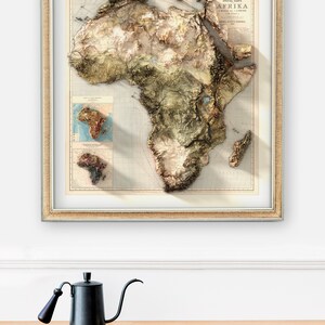 May include: A framed vintage map of Africa with a 3D embossed effect. The map is in shades of brown, green, and blue, and includes details like rivers, mountains, and coastlines. The title "SPEZIAL-KARTE AFRIKA" is printed at the top of the map.