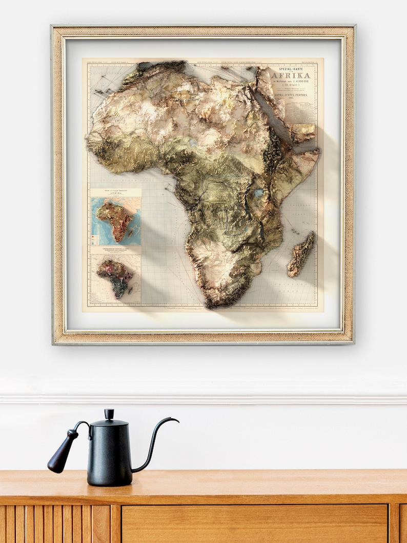 May include: A framed vintage map of Africa with a 3D embossed effect. The map is in shades of brown, green, and blue, and includes details like rivers, mountains, and coastlines. The title "SPEZIAL-KARTE AFRIKA" is printed at the top of the map.