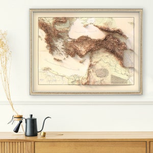 Pode incluir: Um mapa topogr&aacute;fico em relevo de estilo vintage do M&eacute;dio Oriente, emoldurado numa moldura castanho claro. O mapa apresenta um relevo detalhado e em relevo das montanhas e vales da regi&atilde;o, com um esquema de cores castanho claro e bege.