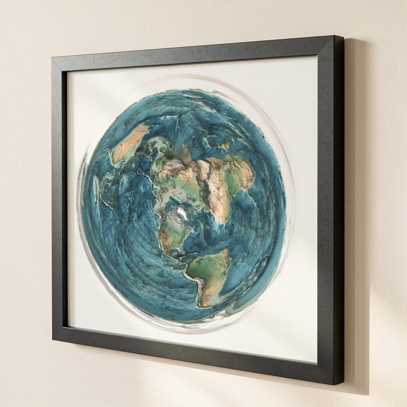 May include: A framed artwork depicting a flat-earth map. The artwork features a detailed, textured rendering of the continents in shades of green and brown, surrounded by blue oceans. The artwork is encased in a black frame.