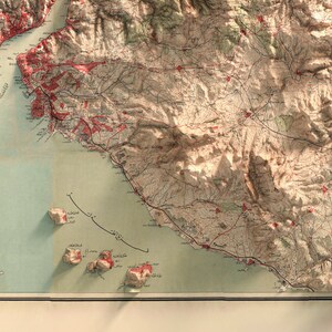 May include: An antique map of a mountainous region with red markings and Arabic text. The map shows a coastline with islands and a body of water. The map is printed on aged paper with a cream background.