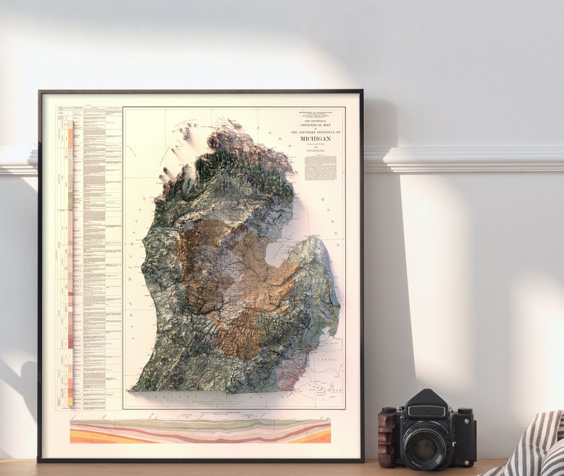 Puede incluir: Un mapa topogr&aacute;fico de estilo vintage de Michigan, que muestra las caracter&iacute;sticas f&iacute;sicas del estado en un estilo de relieve 3D. El mapa est&aacute; impreso en papel de color crema con acentos marrones, verdes y amarillos. El t&iacute;tulo "Topographic Map of Michigan" est&aacute; impreso en la parte superior del mapa.