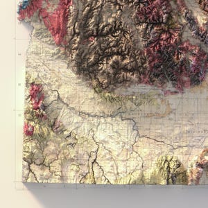 May include: A detailed, vintage-style map with topographic features. The map displays a relief of mountains and valleys in shades of brown, pink, and green. The map has a weathered appearance, with grid lines and text labels.