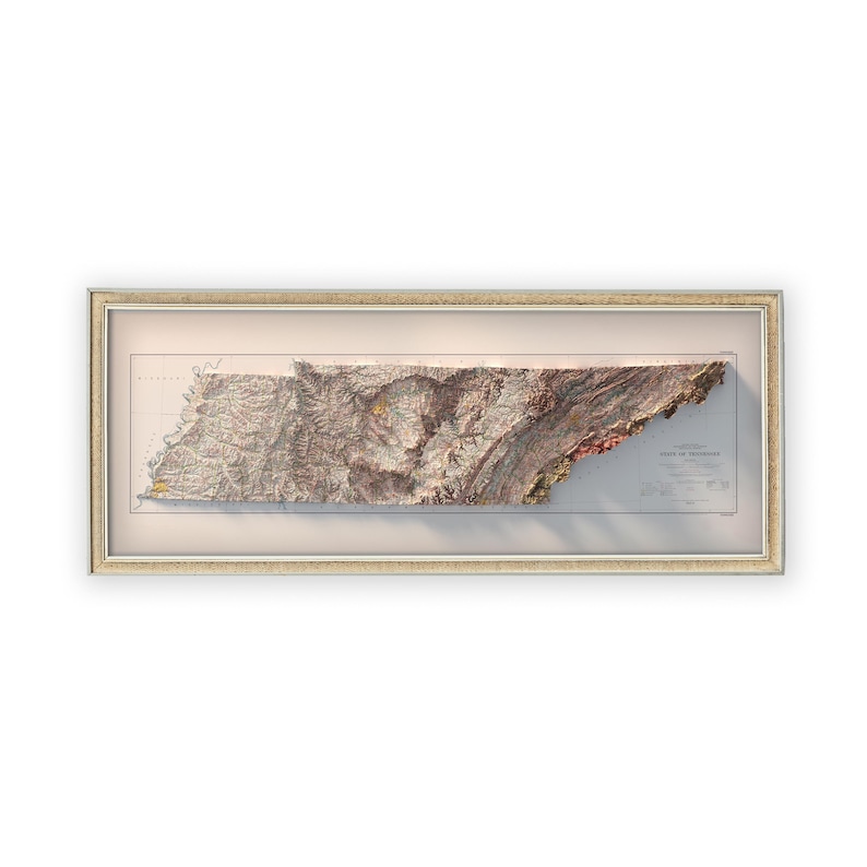 May include: A framed 3D relief map of the state of Tennessee. The map is printed on a cream-colored background and shows the state's topography with brown, green, and red colors. The map is framed in a light brown frame.