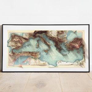 May include: A framed vintage map of the Mediterranean Sea with a 3D embossed effect. The map shows the coastline of Italy, Greece, Turkey, and other countries surrounding the sea. The map is printed on a cream-colored paper with brown and blue accents.