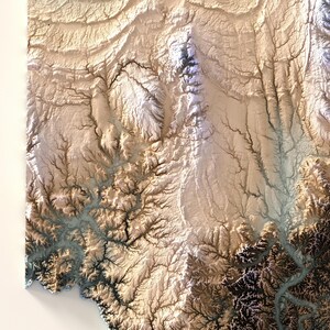 K&ouml;nnte beinhalten: Eine detaillierte, dreidimensionale topografische Karte mit Reliefwirkung. Die Karte zeigt ein komplexes Netzwerk von Canyons, T&auml;lern und Bergen in Braun-, Beige- und Wei&szlig;t&ouml;nen, wobei dunklere Bereiche Schatten oder niedrigere H&ouml;henlagen andeuten. Der Gesamteffekt ist eine strukturierte, k&uuml;nstlerische Darstellung einer Landschaft.