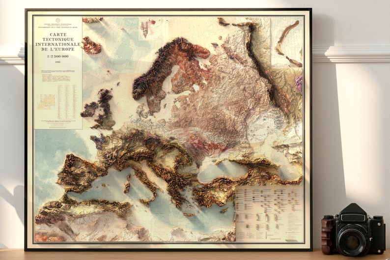 Pu&ograve; includere: Una mappa dell'Europa in stile vintage con un effetto 3D testurizzato. La mappa &egrave; stampata su uno sfondo color crema con accenti marroni, dorati e blu. Il titolo "CARTE TECTONIQUE INTERNATIONALE DE L'EUROPE" &egrave; stampato nella parte superiore della mappa.