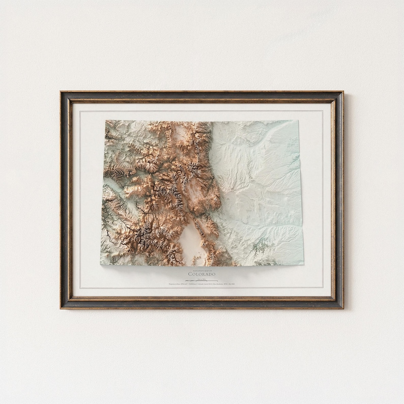 K&ouml;nnte beinhalten: Gerahmte 3D-Topografische Karte von Colorado mit detaillierter Reliefdarstellung in Braun-, Beige- und Wei&szlig;t&ouml;nen. Die Karte ist in einem dunkelbraunen Rahmen mit wei&szlig;em Passepartout eingefasst, und das Wort "Colorado" ist unten aufgedruckt.