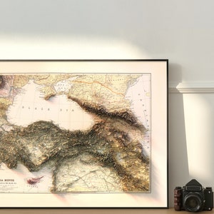 May include: A vintage map of Asia Minor, also known as Anatolia, with the text "ASIA MINOR THE EASTERN SHORE OF THE BLACK SEA" printed at the bottom. The map is framed in black and features a detailed topographic relief of the region.