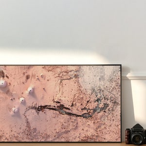May include: A framed abstract art print with a pink and black colour scheme. The print features a textured, abstract design with a black river-like shape running through the centre.