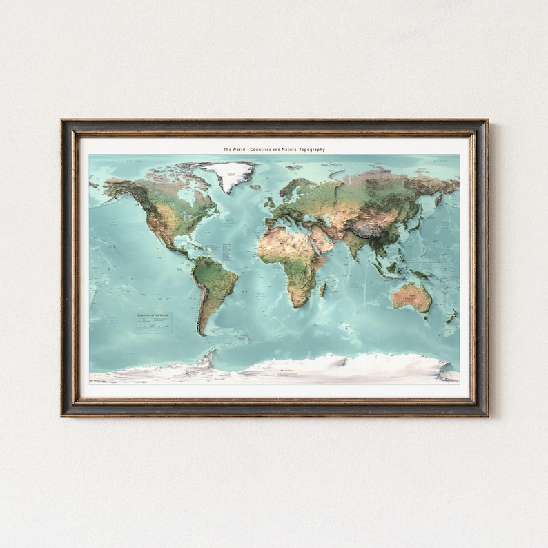May include: A framed world map titled The World - Countries and Natural Topography, featuring detailed landmasses in shades of green and brown against a light blue ocean, with white polar regions and a dark brown frame with gold trim.