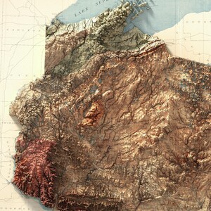 Puede incluir: Un mapa de estilo vintage de una regi&oacute;n con topograf&iacute;a detallada, que muestra r&iacute;os, monta&ntilde;as y valles en tonos marrones, verdes y azules.
