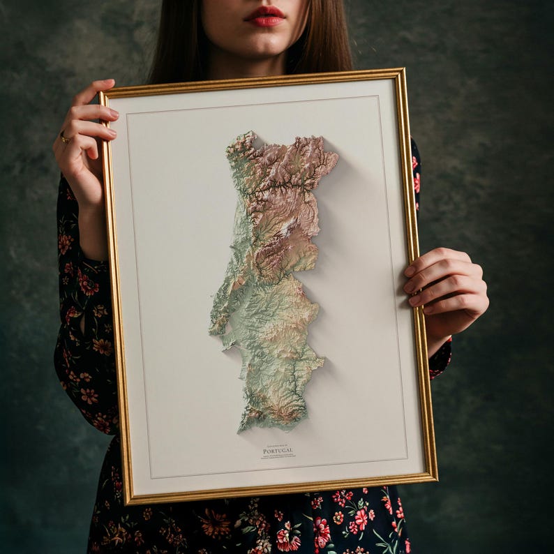 May include: Framed 3D relief map of Portugal, showcasing the country's topography in shades of green, brown, and beige. The map is set against a white background within a gold-colored frame. The word "PORTUGAL" is printed at the bottom.