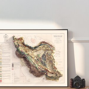 May include: A vintage, detailed, topographic map of Iran, printed in black and white with coloured geological markings. The map is framed in a black frame and is hanging on a white wall.