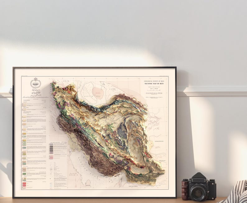 May include: A vintage, detailed, topographic map of Iran, printed in black and white with coloured geological markings. The map is framed in a black frame and is hanging on a white wall.