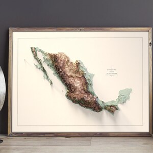 May include: Framed 3D relief map of Mexico, showcasing the country's topography in shades of brown, green, and beige. The map is set against a cream-colored background, enclosed in a wooden frame. The map is labeled with the country's name.