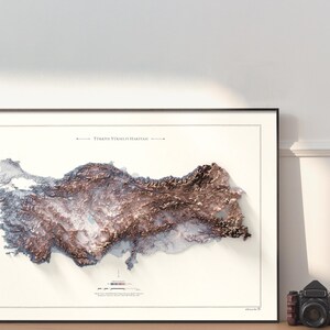 May include: A framed map of Turkey with a 3D relief effect, showing the country's topography in shades of brown and white. The title "T&uuml;rkiye Y&uuml;kseklik Haritası" is printed at the top of the map.