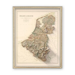 Pode incluir: Um mapa vintage da Holanda e da B&eacute;lgica com um efeito de relevo 3D. O mapa &eacute; impresso em papel cor de creme e emoldurado em uma moldura de madeira clara.