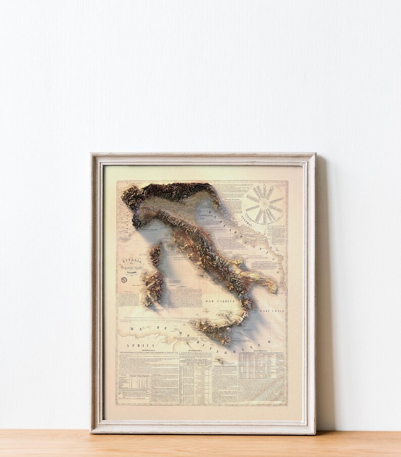 May include: A vintage-style map of Italy in a white frame. The map is a 3D relief map with a beige background and brown and green topographical features. The map is surrounded by text and a compass rose.