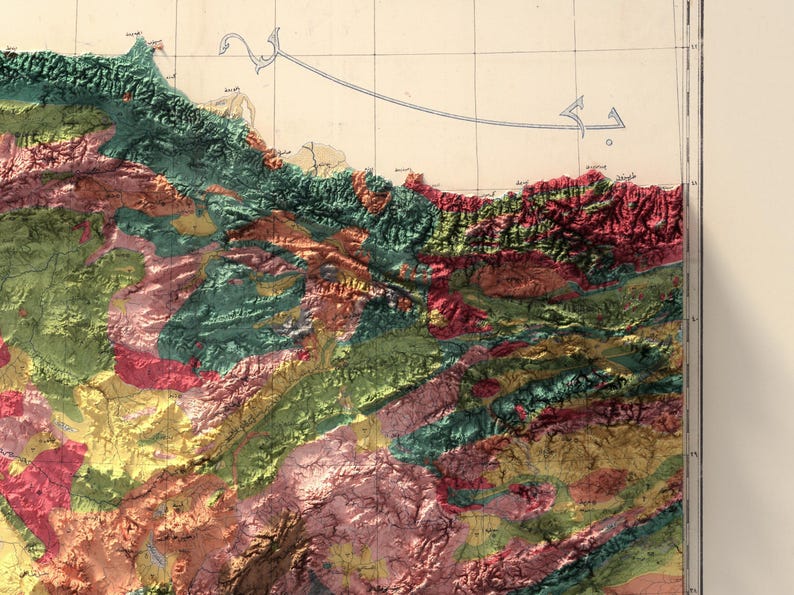 May include: A detailed topographic map of a mountainous region with various shades of green, red, and yellow representing different elevations. The map features a coastline and a few Arabic script labels.