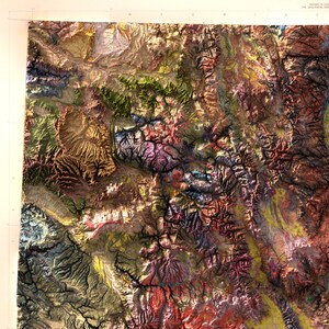 May include: A detailed, colorful topographic map of a mountainous region. The map features a variety of colors, including shades of green, brown, purple, and yellow, representing different elevations and geological features. The map is a detailed representation of the terrain.