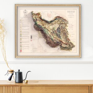 May include: A vintage, detailed, hand-coloured relief map of Iran, showing the country's topography and geological features. The map is framed in a light wood frame and has a title at the top: "GEOLOGICAL SKETCH OF PERSIA,  TECTONIC MAP OF PERSIA, BY MAJOR F.R.S.  PUBLISHED BY THE ROYAL GEOGRAPHICAL SOCIETY, LONDON, 1896."
