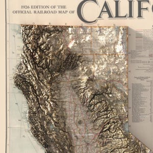K&ouml;nnte beinhalten: Eine Vintage-Karte von Kalifornien aus dem Jahr 1926 mit dem Titel "1926 Edition of the Official Railroad Map of California". Die Karte zeigt die Topographie des Staates mit braunen und wei&szlig;en Schattierungen sowie ein Netz von Eisenbahnlinien in Rot und Schwarz.