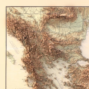 Pode incluir: Um mapa vintage da Pen&iacute;nsula Balc&acirc;nica, mostrando o terreno em tons de marrom e verde. O mapa est&aacute; etiquetado em escrita &aacute;rabe, com nomes de lugares como "Alb&acirc;nia" e "Gr&eacute;cia" vis&iacute;veis.