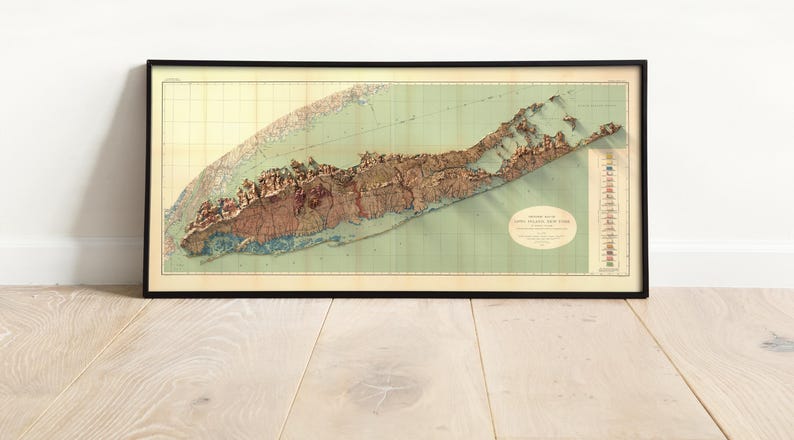 May include: A vintage map of Long Island, New York, in a black frame. The map is a relief map, showing the topography of the island. The map is in shades of brown, green, and blue. The title of the map is "Long Island, New York, Relief Map" and is printed in the lower right corner.
