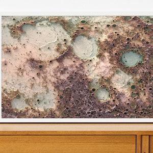 May include: Abstract art print featuring a textured, cratered surface in shades of brown, pink, and green. The print has a distressed, vintage look.