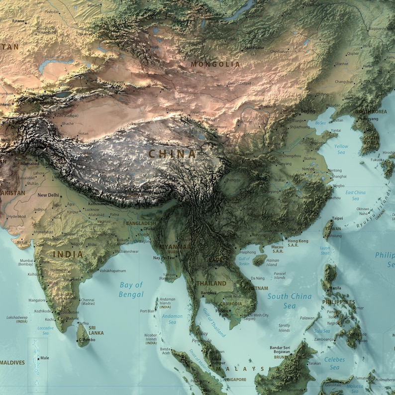 May include: A physical map of East and Southeast Asia featuring a relief-style design. The terrain displays varied elevations in shades of green, brown, and tan, with labeled countries, cities, and bodies of water including China, India, and the South China Sea.