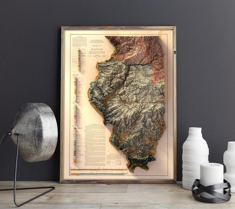 May include: A vintage map of Illinois in a wooden frame. The map is a relief map, showing the topography of the state. The map is in shades of brown, green, and blue.