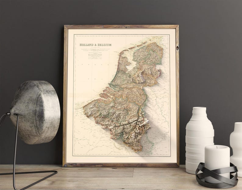 Pode incluir: Um mapa vintage da Holanda e da B&eacute;lgica em uma moldura de madeira. O mapa &eacute; em estilo relevo, mostrando a topografia da regi&atilde;o. O mapa &eacute; impresso em papel creme com acentos marrons e verdes.