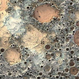 May include: A close-up of a textured surface with a variety of craters and holes. The surface is a mix of light brown, gray, and white colors.
