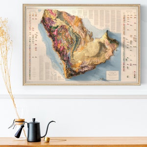 May include: A vintage-style topographic map of the Arabian Peninsula, showing the geological formations and features of the region. The map is framed in a gold-coloured frame and has a light blue background with brown, yellow, and pink coloured geological features.