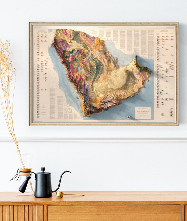 May include: A vintage-style topographic map of the Arabian Peninsula, showing the geological formations and features of the region. The map is framed in a gold-coloured frame and has a light blue background with brown, yellow, and pink coloured geological features.