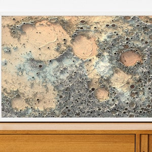May include: A digital art print featuring a close-up of a textured surface with craters and holes in shades of gray, beige, and light blue.