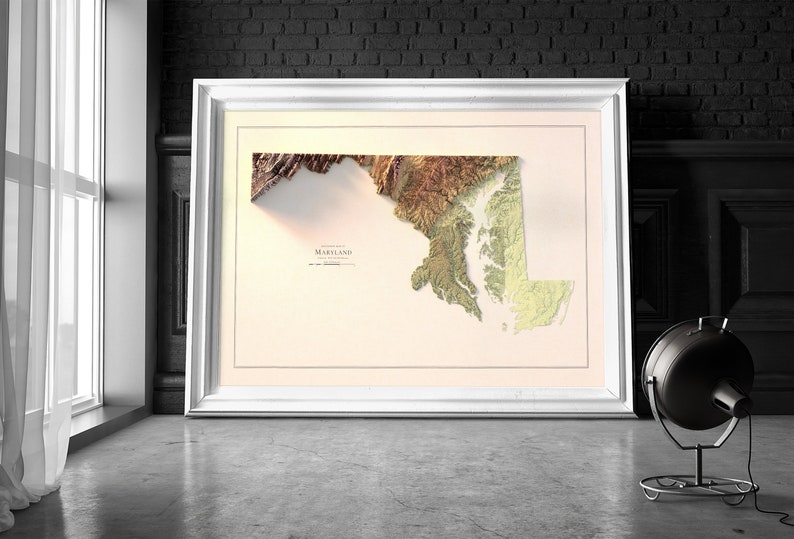 May include: A framed 3D relief map of Maryland with a beige background. The map is in shades of brown, green, and yellow, showing the state's topography. The word "Maryland" is printed in black at the bottom of the map.