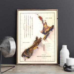 May include: A vintage geological map of New Zealand, framed in a brown wood frame. The map shows the different geological formations of the North and South Islands, with a key to the different rock types. The map is titled "Sketch Map Geology of New Zealand by Arthur S. Eakins."