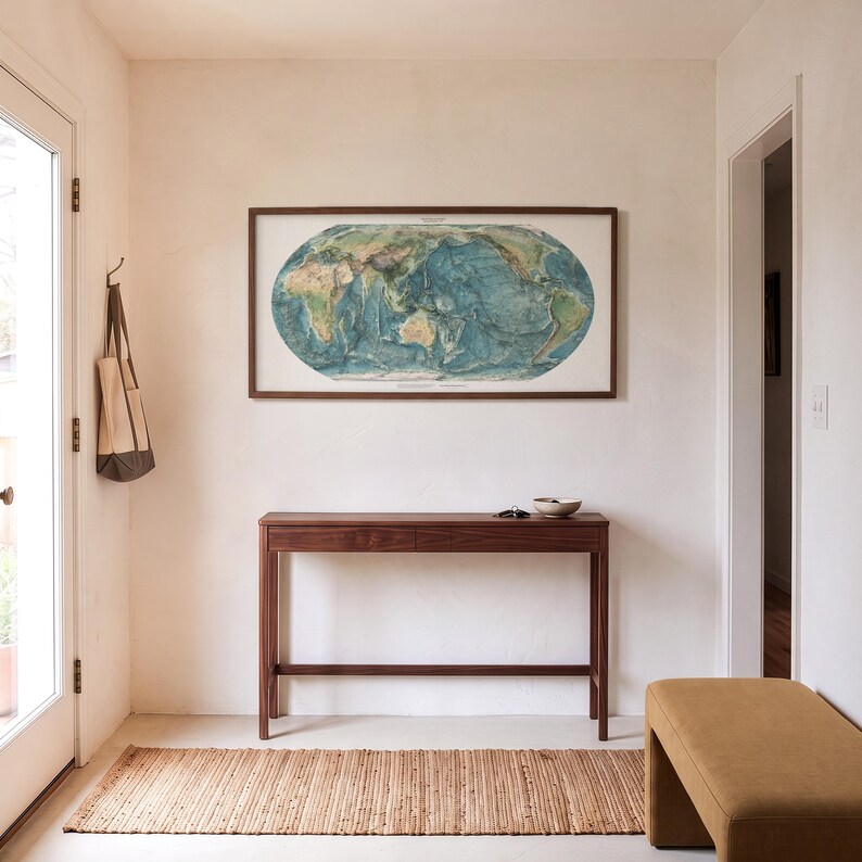 May include: A rectangular wooden console table with a single drawer, positioned beneath a framed oval world map print. The table features four slender legs and a horizontal support bar, crafted from dark brown wood with a smooth finish.