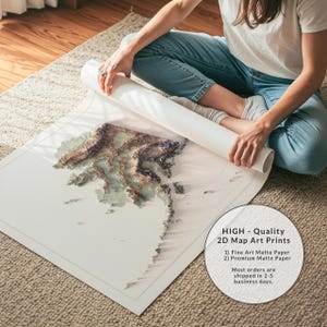 May include: A detailed 2D map art print, partially unrolled, showcasing a topographical landscape with brown and green hues. The print is on matte paper, with a white border. Text on the image reads "HIGH - Quality 2D Map Art Prints".