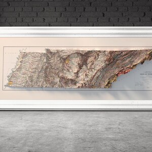 May include: A framed vintage map of the state of Tennessee with a raised relief design. The map is printed on cream-colored paper and shows the state's topography with brown, green, and red colors.