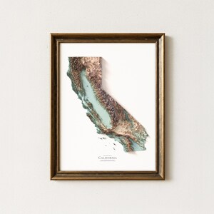 Op de afbeelding: Een ingelijste 3D topografische kaart van Californi&euml;, met gedetailleerd reli&euml;f in bruin, groen en blauw. De kaart staat tegen een witte achtergrond in een goudkleurige lijst. Het woord "California" staat onderaan afgedrukt.
