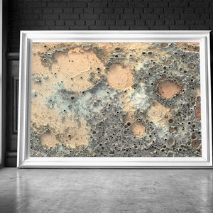 May include: Abstract art print featuring a textured, cratered surface in shades of beige, brown, and blue. The print has a distressed, vintage look.