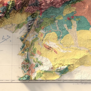 May include: A vintage map of a coastal region showing detailed geological formations. The map is in shades of yellow, green, red, and blue, with a grid overlay. The map includes text in Arabic.